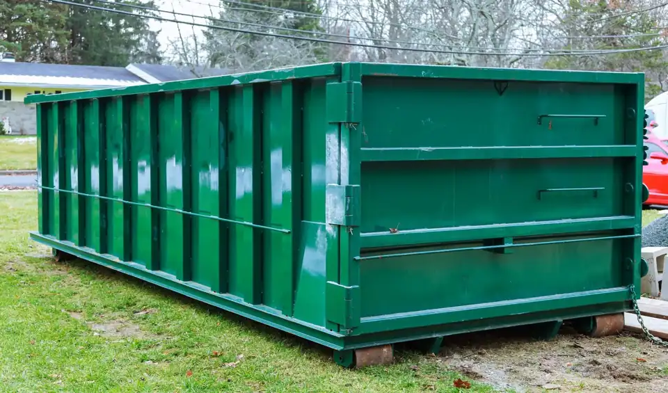 Green roll-off dumpster set on wooden boards